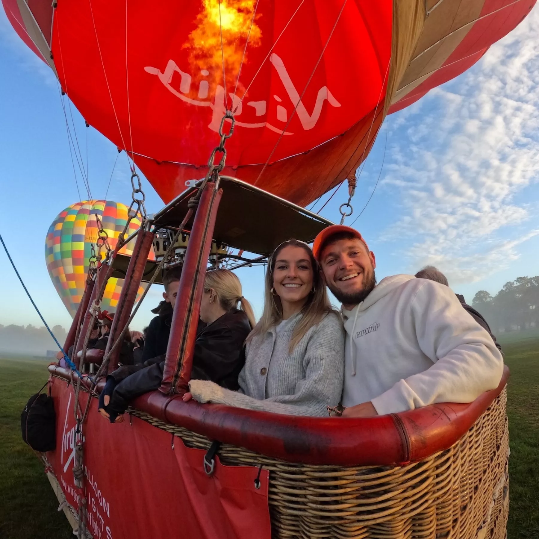 A smiling couple inside a balloon basket, ready to lift off for their sunrise flight